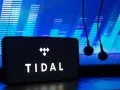 Smartfon z logo TIDAL i słuchawkami na tle ekranu z wizualizacją dźwięku.