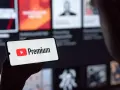 Telefon wyświetla logo YouTube Premium na tle ekranu z innymi treściami.