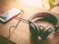 Słuchawki i smartfon leżące na drewnianym stole.