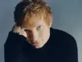Ed Sheeran w czarnym golfie, opierający głowę na dłoni.