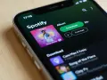 Ekran telefonu z aplikacją Spotify, widoczna okładka albumu i przyciski pobierania.