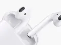 Białe słuchawki AirPods z etui ładującym na białym tle.