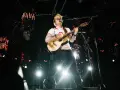 Ed Sheeran gra na gitarze na scenie w białej koszulce z polskim godłem.