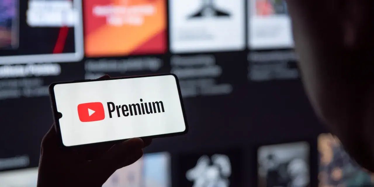 Telefon wyświetla logo YouTube Premium na tle ekranu z innymi treściami.