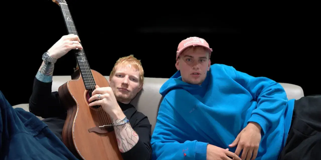 Ed Sheeran z gitarą i młody mężczyzna w niebieskiej bluzie siedzą na kanapie.