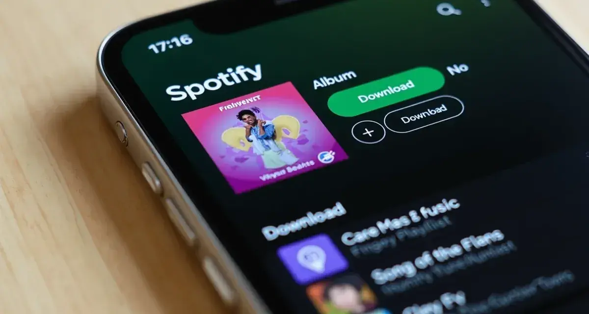 Ekran telefonu z aplikacją Spotify, widoczna okładka albumu i przyciski pobierania.