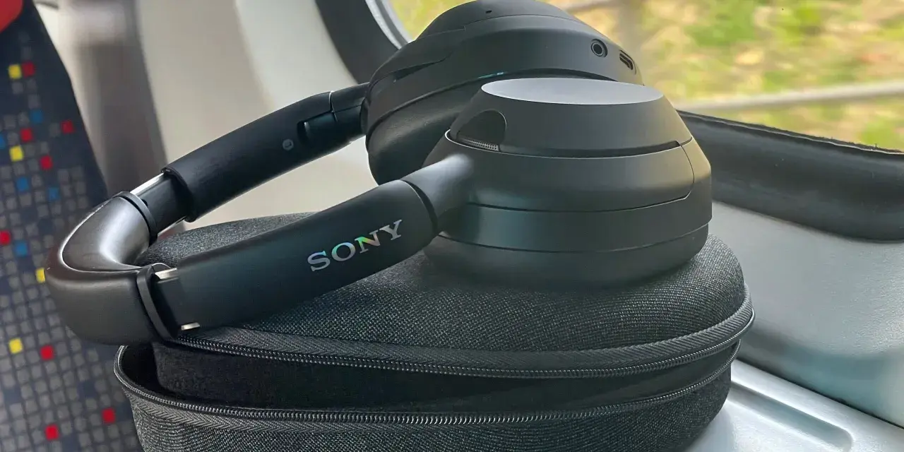 Czarne słuchawki Sony leżą na etui, na stoliku w pociągu.