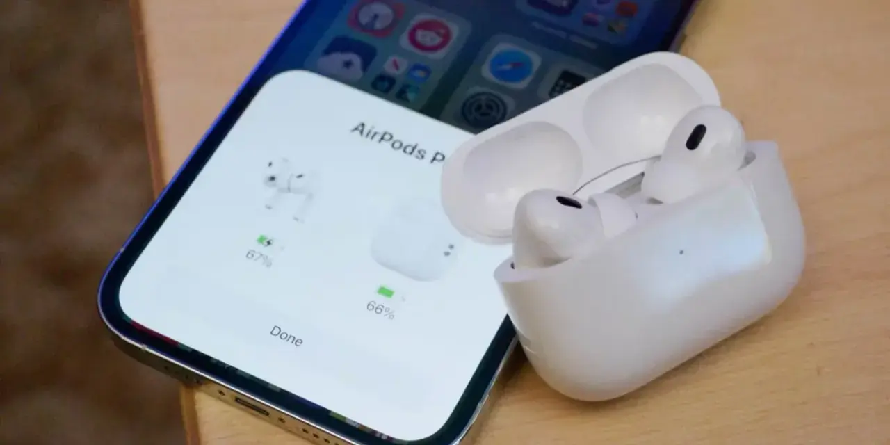 iPhone z otwartym etui AirPods Pro, pokazującym stan naładowania słuchawek.