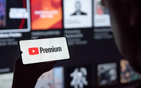 Telefon wyświetla logo YouTube Premium na tle ekranu z innymi treściami.