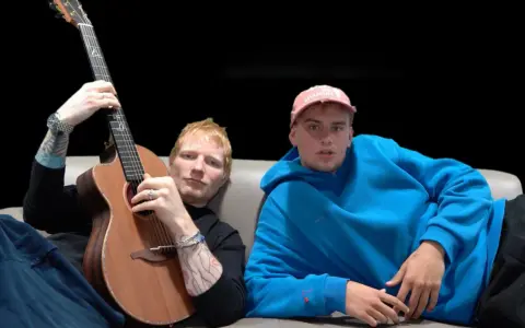 Ed Sheeran z gitarą i młody mężczyzna w niebieskiej bluzie siedzą na kanapie.