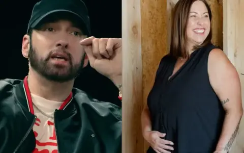 Eminem w czapce i czarnej kurtce obok uśmiechniętej kobiety w czarnej bluzce.