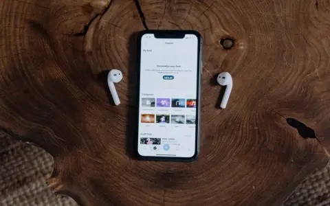 iPhone z AirPods na drewnianym tle.