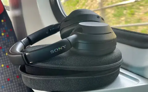 Czarne słuchawki Sony leżą na etui, na stoliku w pociągu.