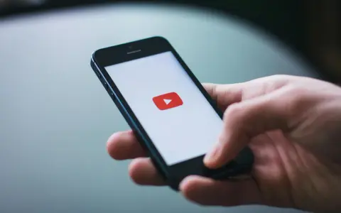 Dłoń trzymająca smartfon z logo YouTube.