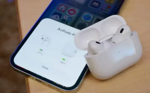 iPhone z otwartym etui AirPods Pro, pokazującym stan naładowania słuchawek.