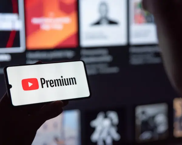 Telefon wyświetla logo YouTube Premium na tle ekranu z innymi treściami.