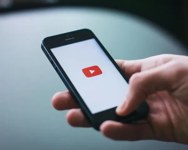 Dłoń trzymająca smartfon z logo YouTube.
