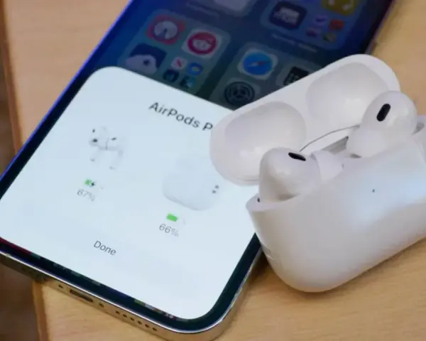 iPhone z otwartym etui AirPods Pro, pokazującym stan naładowania słuchawek.