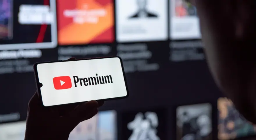 Telefon wyświetla logo YouTube Premium na tle ekranu z innymi treściami.