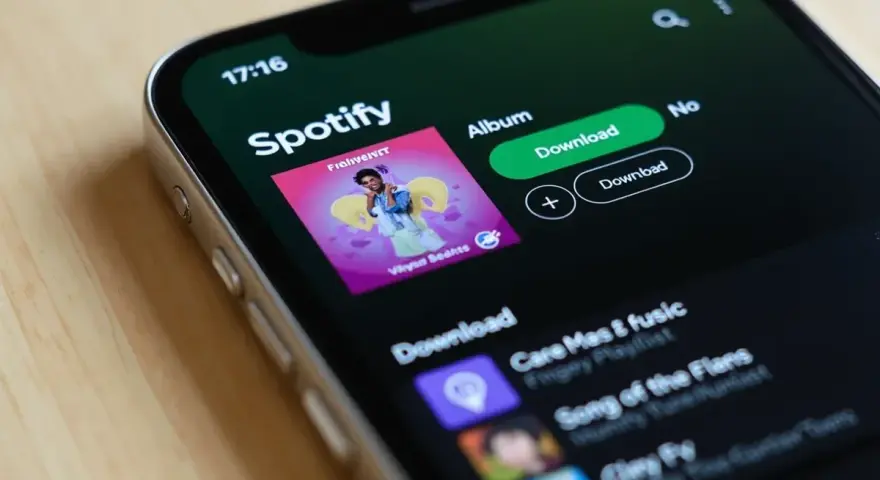 Ekran telefonu z aplikacją Spotify, widoczna okładka albumu i przyciski pobierania.
