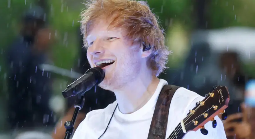 Ed Sheeran grający na gitarze podczas deszczu.