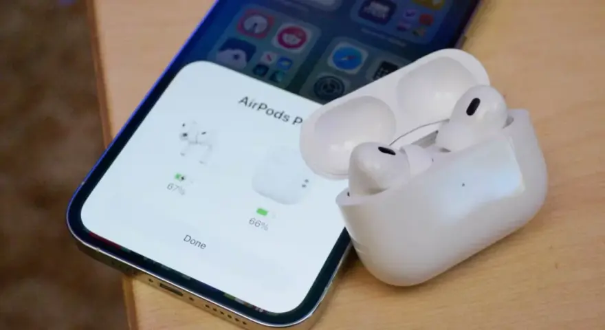 iPhone z otwartym etui AirPods Pro, pokazującym stan naładowania słuchawek.